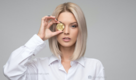 A woman holding a coin in front of her eye
