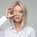 A woman holding a coin in front of her eye
