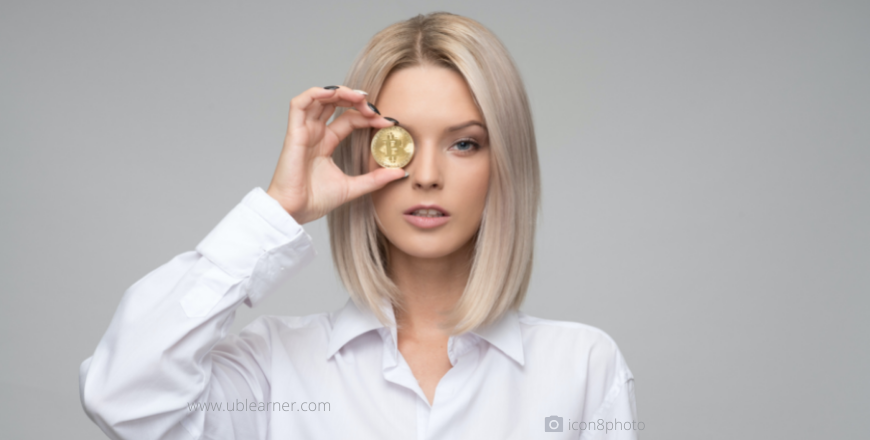 A woman holding a coin in front of her eye